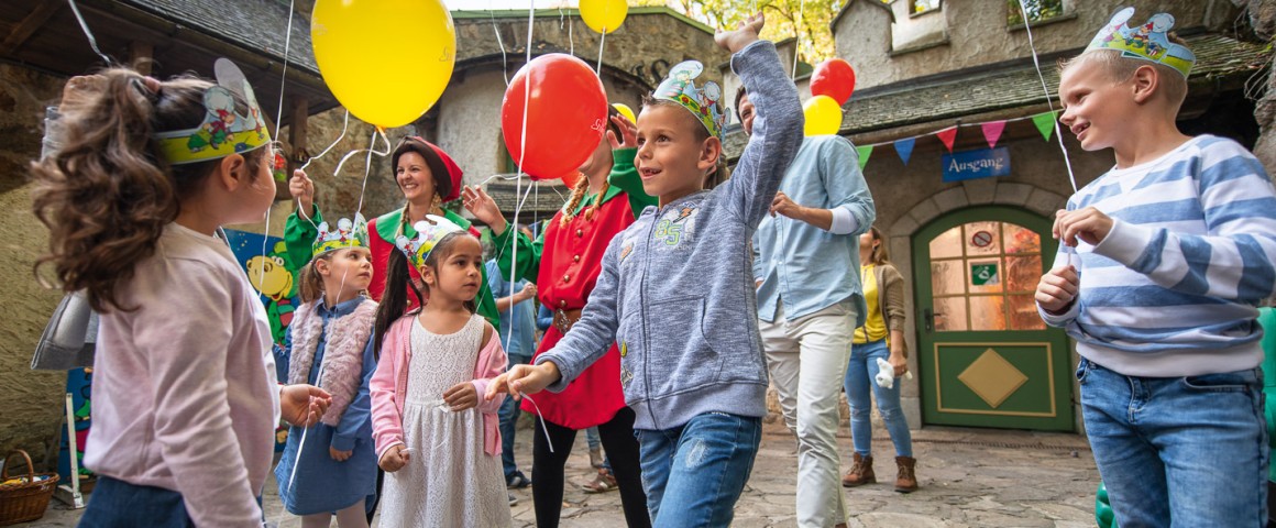 Kinder tanken fröhlich auf einer Kinderparty mit Luftballons in der Hand.