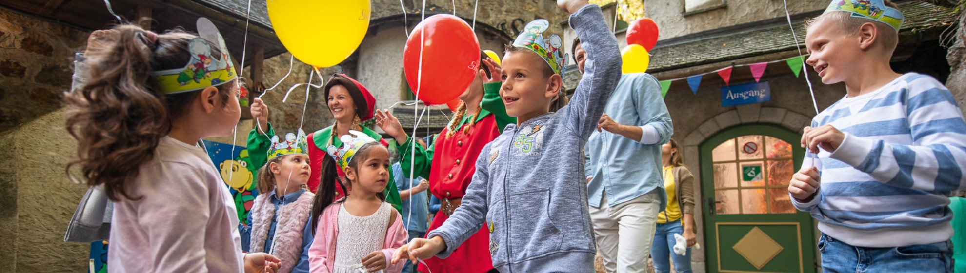 Kinder tanken fröhlich auf einer Kinderparty mit Luftballons in der Hand.