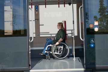 Rollstuhlfahrer steigt in Bus ein.