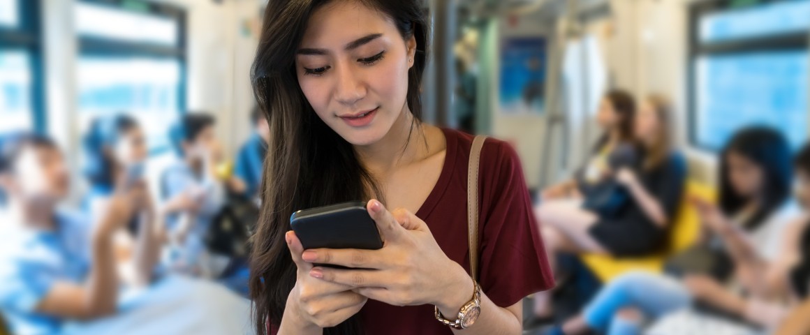 Eine Frau sieht auf ihr Smartphone in der Straßenbahn.