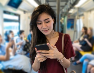 Eine Frau sieht auf ihr Smartphone in der Straßenbahn.