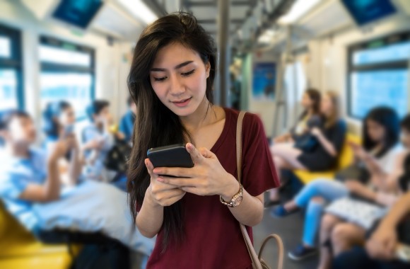 Eine Frau sieht auf ihr Smartphone in der Straßenbahn.