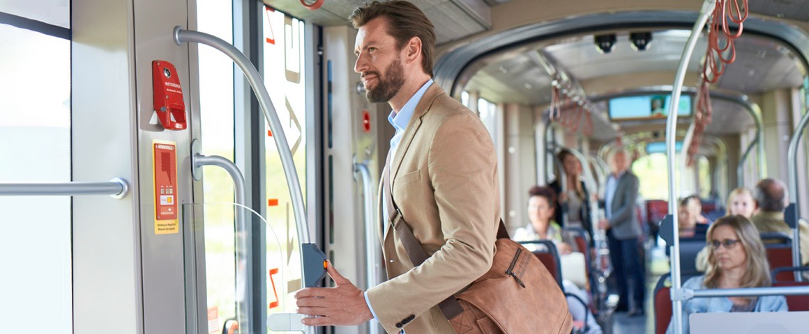 Mann auf dem Weg zur Arbeit in der Straßenbahn drückt auf den Halteknopf und wartet auf den Ausstieg.