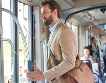 Mann auf dem Weg zur Arbeit in der Straßenbahn drückt auf den Halteknopf und wartet auf den Ausstieg.