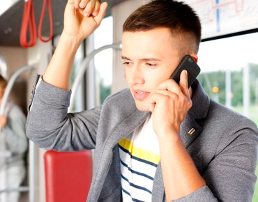 Ein Mann steht in einer Straßenbahn und telefoniert mit dem Handy. 