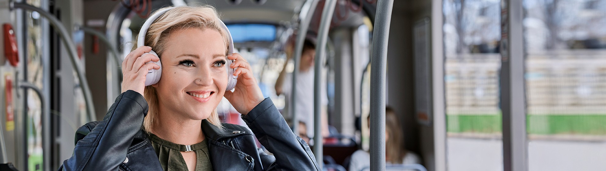 Eine junge Frau hört Musik in der Straßenbahn und trägt Kopfhörer