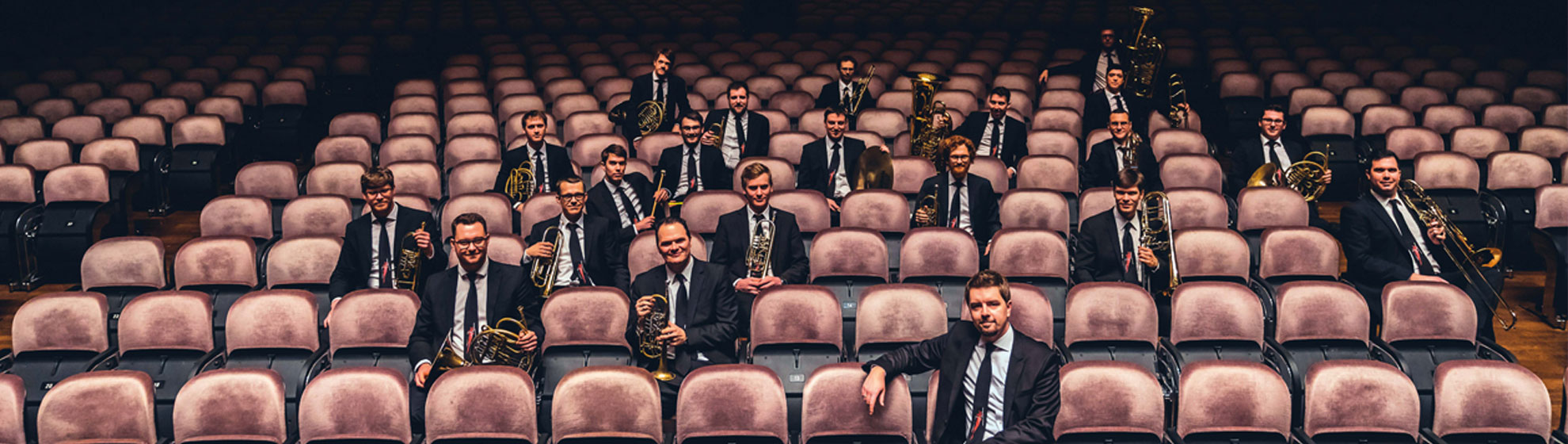 Musiker in dunklen Anzügen (Vienna Brass Connection) sitzen in den Zuschauerreihen eines Theaters. Copyright: Light HuntersPhotography