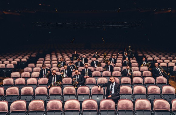 Musiker in dunklen Anzügen (Vienna Brass Connection) sitzen in den Zuschauerreihen eines Theaters. Copyright: Light HuntersPhotography
