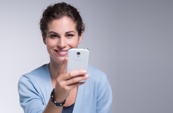 Frau stehend mit Handy in der Hand