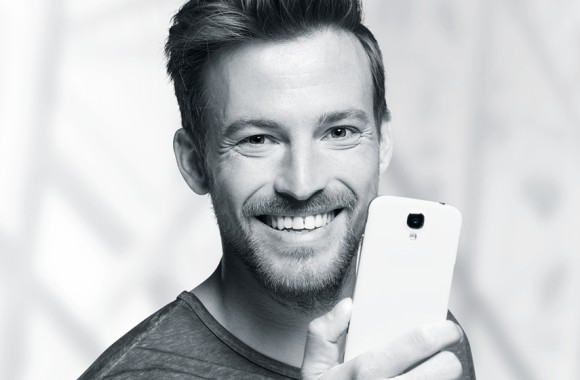 Mann, der sein Smartphone in der Hand vor seinem Gesicht hält.