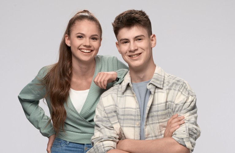 Teenager-Mädchen lehnt sich mit dem Arm an die Schulter eines Teenager-Jungen.