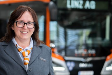 Busfahrerin vor einem Bus der Linz AG Linien lächelt in die Kamera