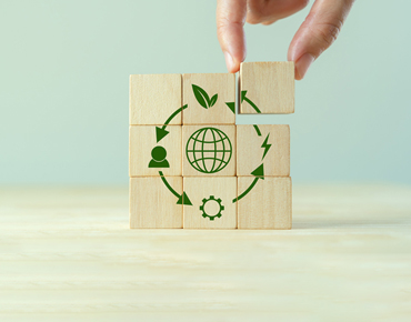 Nachhaltigkeitswürfel aus Holz, auf dem Würfel sind die Symbole der Kreislaufwirtschaft abgebildet
