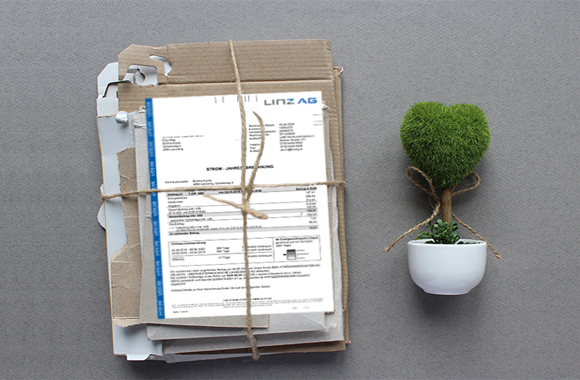 Abbildung eines Stapels Altpapier mit einer LINZ AG-Rechnung und ein grünes Bäumchen in einem Topf