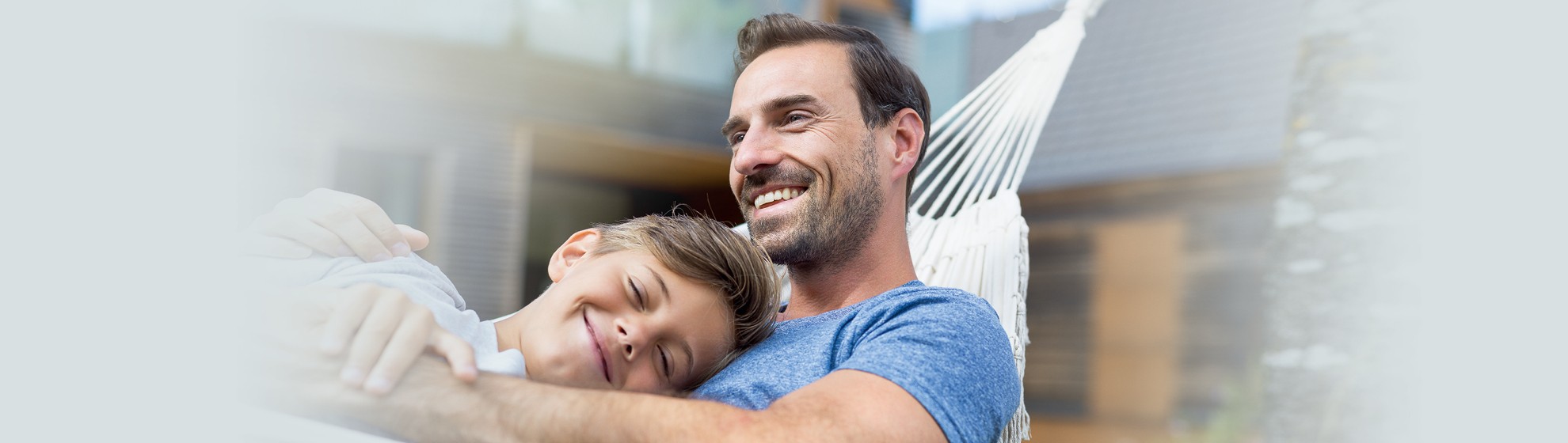 Mann liegt mit seinem Sohn Arm in Arm in der Hängematte 