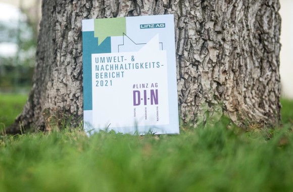 Der Umwelt- und Nachhaltigkeitsbericht 2021 der Linz AG vor einem Baumstamm fotografiert