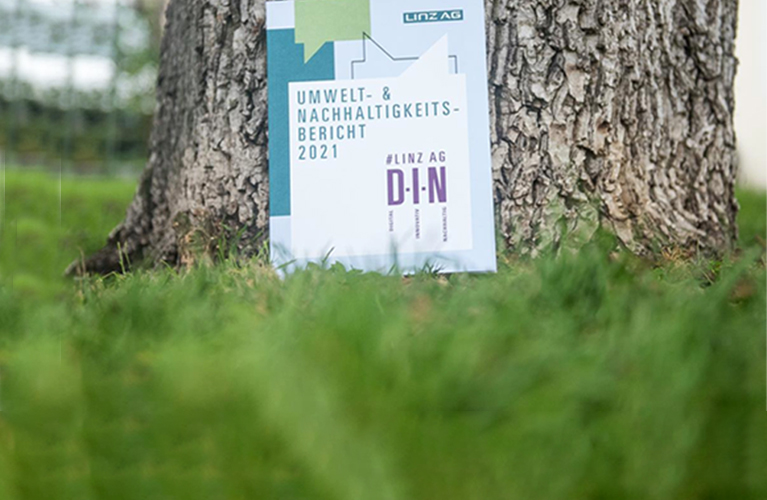 Der Umwelt- und Nachhaltigkeitsbericht 2021 der Linz AG vor einem Baumstamm fotografiert