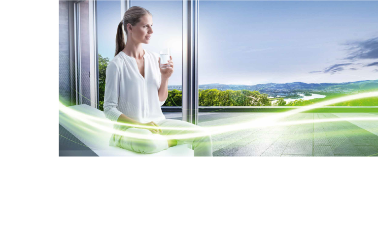 Frau sitzt mit einem Glas Wasser am Fenster und schaut auf Linz hinab