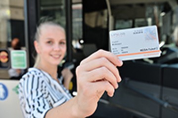 Frau steht vor der Straßenbahn mit einem Mega Ticket in der Hand