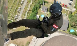 Seiltechnikübungen der Cobra am Kraftwerkskamin. Mann hängt an Seil. Aufnahme aus Vogelperspektive