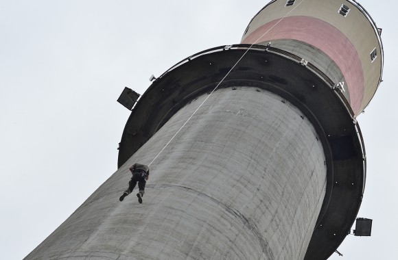 Ein Mitarbeiter der Cobra hängend an einem Seil am Kraftwerkskamin.