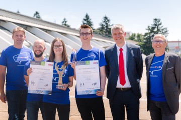 Vorstandsdirektor Josef Siligan mit zwei Mitarbeitern und zwei Lehrlingen, welche eine Auszeichnung und einen Pokal halten