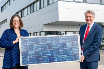 Vorstandsdirektor Josef Siligan und Frau Wagner halten ein Sollarpannel in ihren Händen.