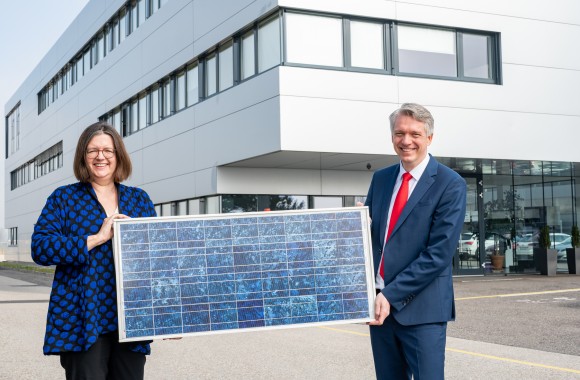 Vorstandsdirektor Josef Siligan und Frau Wagner halten ein Sollarpannel in ihren Händen.