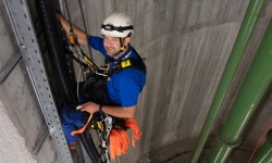 Schacht, Donaudüker, Kletterer hängt im Seil und montiert Kabelkanal.