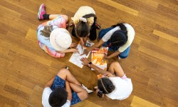 5 Kinder sitzen am Boden und lösen Rätsel, Foto aus der Vogelperspektive