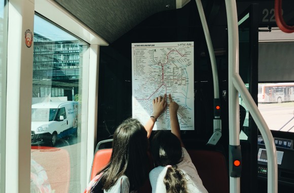 Kinder in Bus der LINZ AG LINIEN betrachten einen Liniennetzplan.