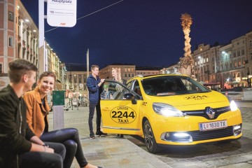 Jugendliche auf dem Linzer Hauptplatz die an der AST-Hasltestelle stehen und zwei weitere die aus einem Taxi steigen.