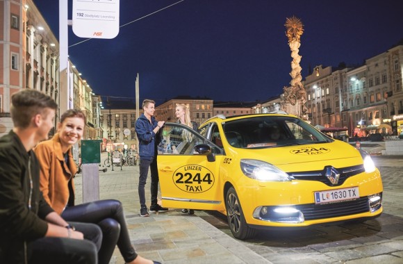 Jugendliche auf dem Linzer Hauptplatz die an der AST-Hasltestelle stehen und zwei weitere die aus einem Taxi steigen.