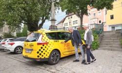 Ein älteres Pärchen die in ein gelbes AST-Taxi einsteigen.