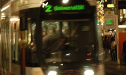 Eine Straßenbahn der LINZ AG LINIEN fährt durch die Landstraße, im Hintergrund die Weihnachtsbeleuchtung der Linzer Innenstadt