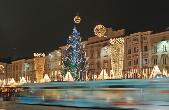Straßenbahn fährt durch die Linzer Innenstadt, die Weihnachtsbeleuchtung ist eingeschaltet.
