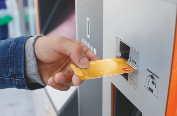 Eine Hand führt eine Kreditkarte in den Fahrscheinautomat