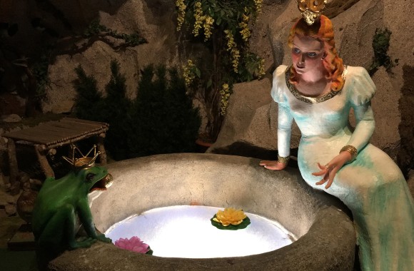 Froschkönig und Prinzessin sitzen am Brunnen.