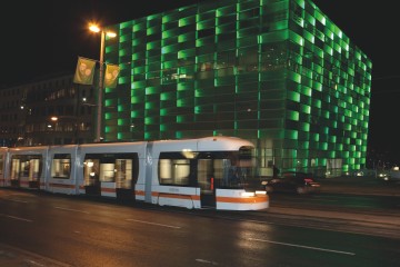 Straßenbahn fährt nachts am Ars Electronica Center vorbei