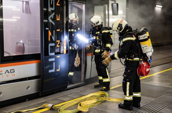 Feuerwehrmänner stehen vor verrauchter Straßenbahn