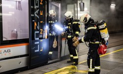 Feuerwehrmänner stehen vor verrauchter Straßenbahn