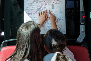 An der Offi-Rallye teilnehmende Kinder zeigen auf einen Fahrplan der LINZ AG LINIEN.