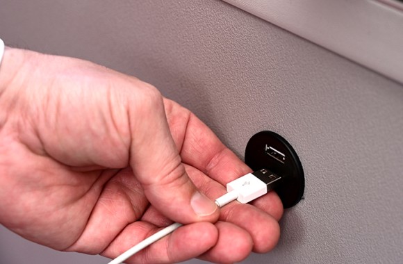 Hand steckt Ladekabel in den USB-Anschluss, welcher in den neuesten E-Autobussen vorzufinden ist