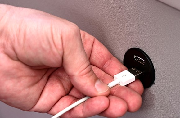 Hand steckt Ladekabel in den USB-Anschluss, welcher in den neuesten E-Autobussen vorzufinden ist