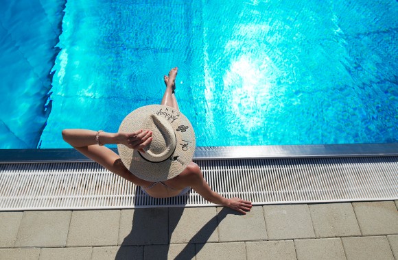 Eine Frau sitzt am Freibad-Beckenrand.