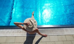 Eine Frau sitzt am Freibad-Beckenrand.