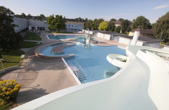 Freibadanlage der Wellnessoase Hummelhof von oben. Verschiedene Becken und Rutsche ist zu sehen