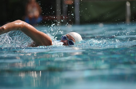 Schwimer mit Schwimmbrille und -haube schwimmt im Sportbecken