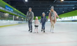 Familie (Mann, Frau, Junge, Mädchen) fahren am Eis