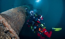 Unterwasseraufnahme in Froschperspektive von Taucher mit Atmungsgerät im Faulturm